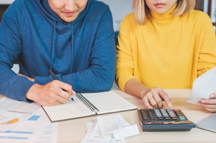 Man and Woman with Notebook and Calculator Working on Budget