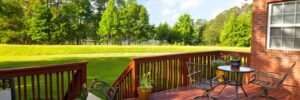 Wooden Backyard Deck with Table and Chairs Looking Out on Green Landscape