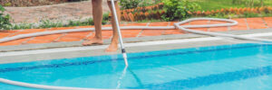 A man vacuuming his pool to keep it clean and well maintained